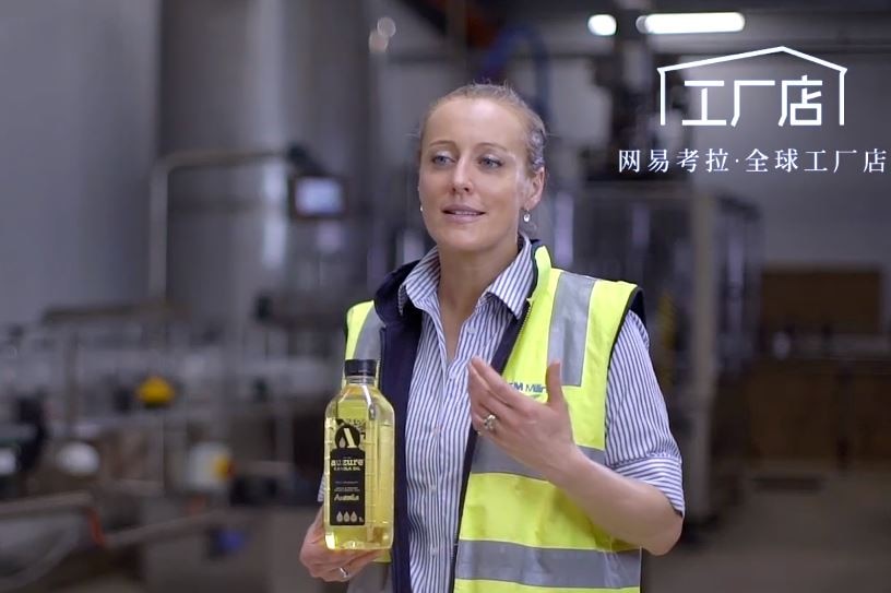 A woman holding a bottle of canola oil presenting to camera