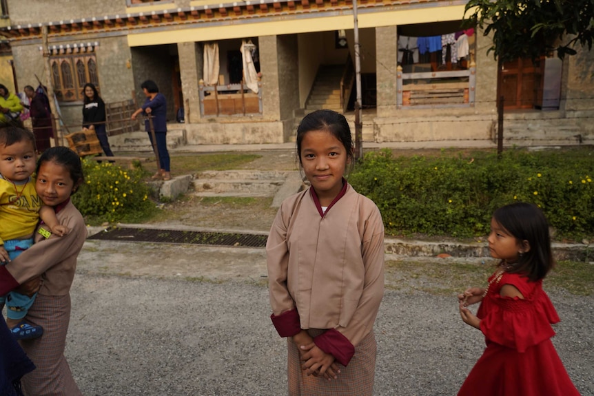 A girl standing in front of her home in Bhutan.