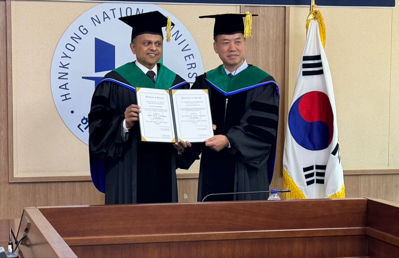 Dois homens com vestes acadêmicas e placas de morteiro sorriem e se abraçam 