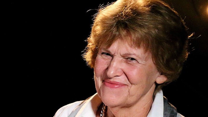 Woman smiles with black backdrop