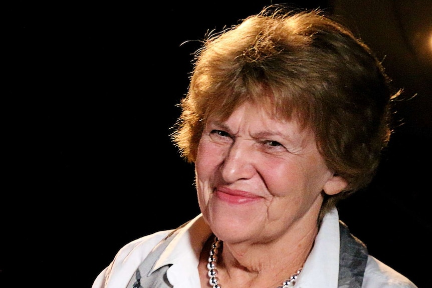 Woman smiles with black backdrop