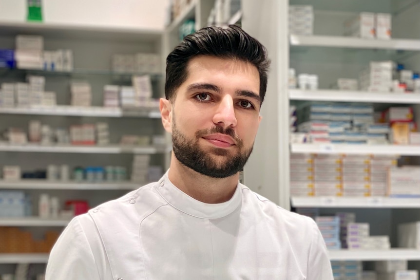 A man with a beard standing inside a pharmacy.