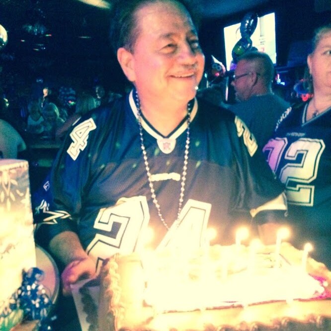 A man in a football jersey holding a birthday cake and smiling