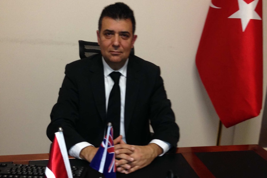 Sydney's Turkish consul general Melih Karalar sits at his desk, flanked by Turkey's flag.