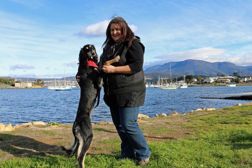 A woman stand with her dog in Hobart.