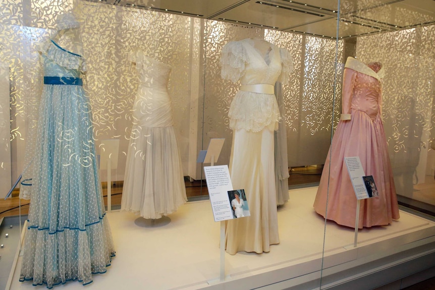 A person looks at some of Princess Diana's dresses on display at an exhibition.