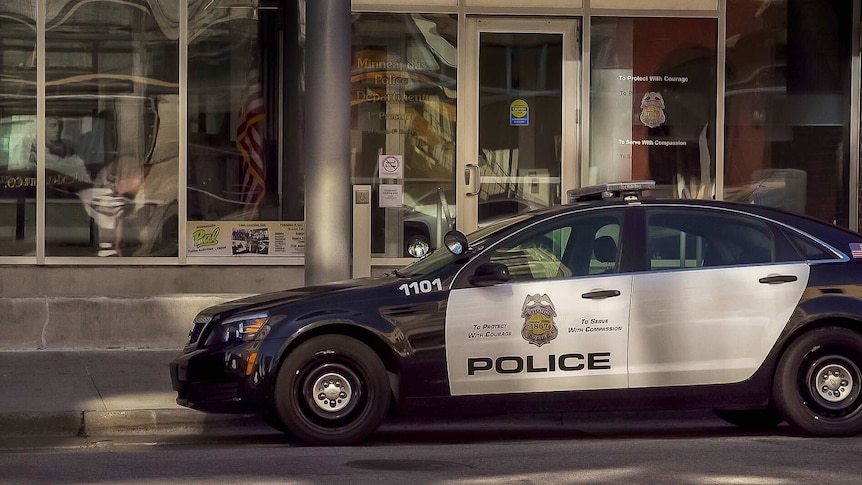 An American police car sits out front of Minneapolis police glass shopfront