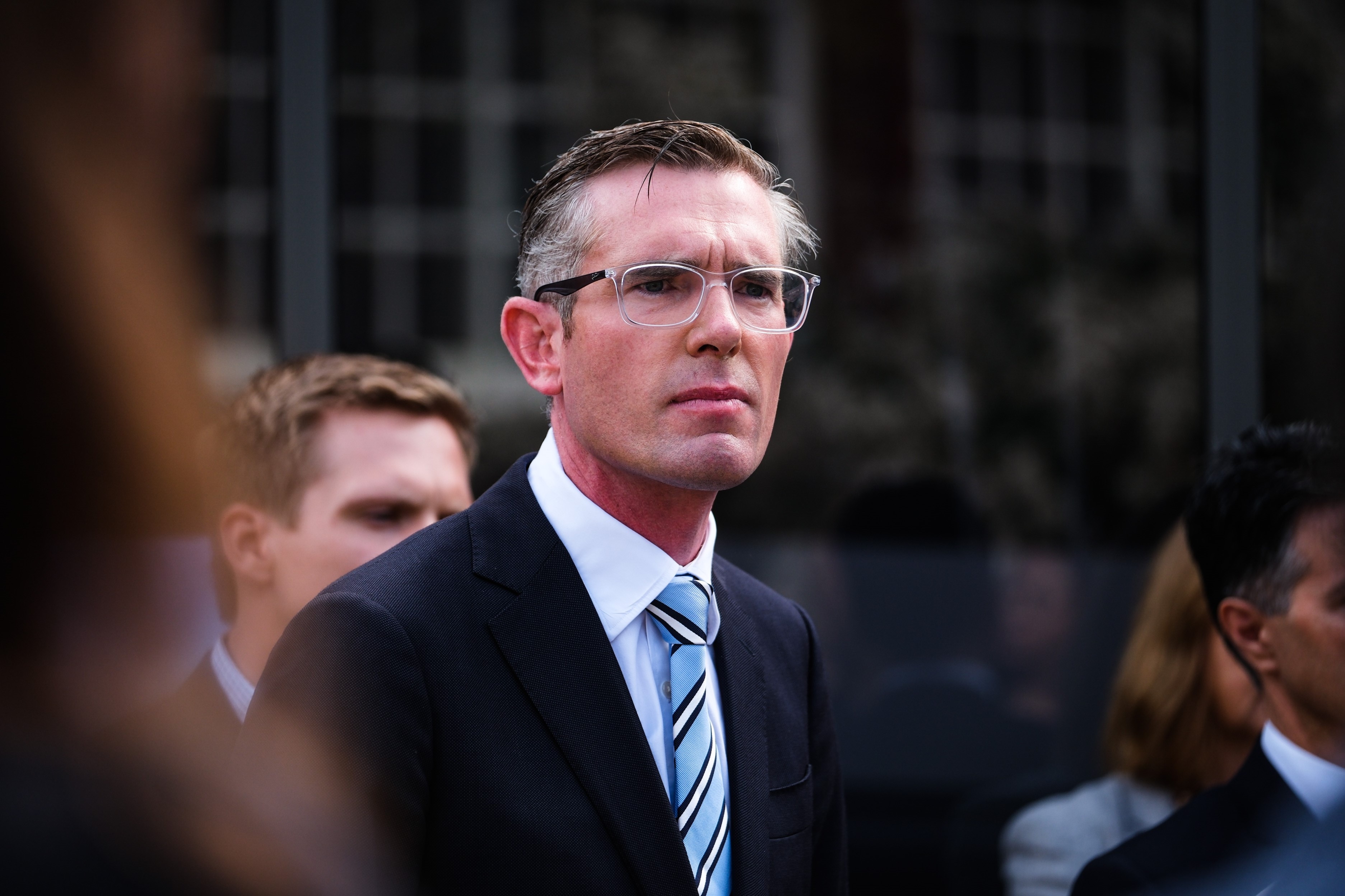 a man wearing glasses standing outdoors in front of a media pack 