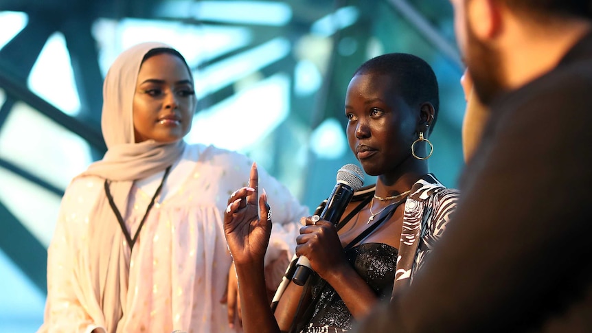 Model Adut Akech on stage with a microphone at Melbourne Fashion Week.