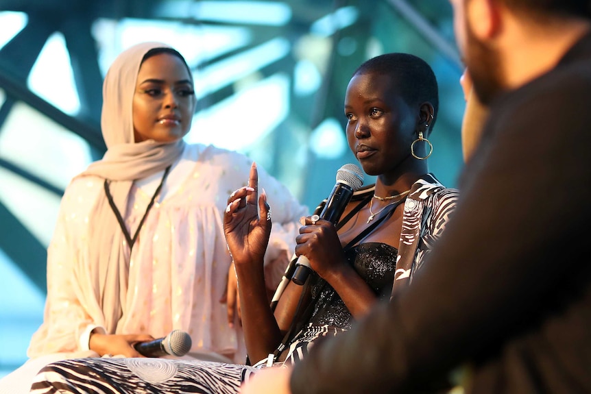 Model Adut Akech on stage with a microphone at Melbourne Fashion Week.