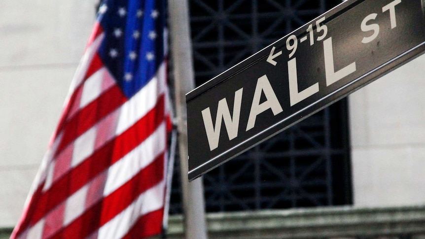 a US flag is shown behind a Wall st street sign