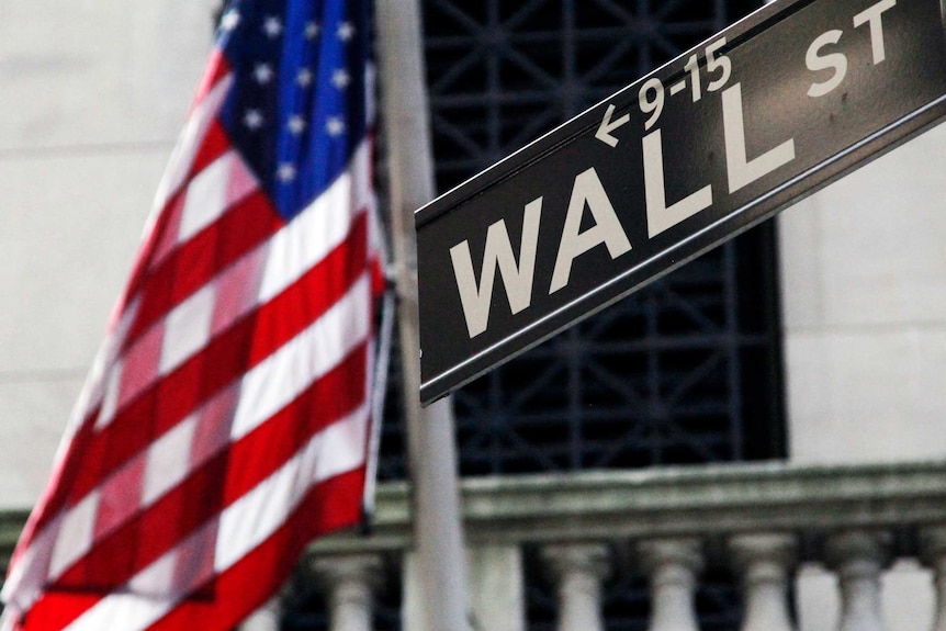 a US flag is shown behind a Wall st street sign