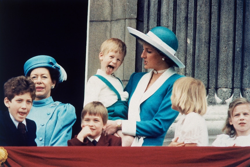 A yoing Prince Harry sits on Princess Diana's hip and sticks his tongue out on the balcony during the Platinum Jubilee.