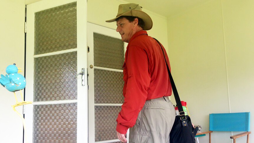 A Queensland Health staffer knocking on the verandah door of a house in Townsville