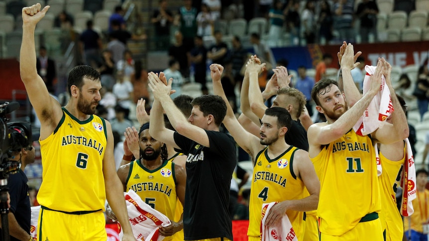 Australian Boomers stand with their hand up applauding wearing gold singles.