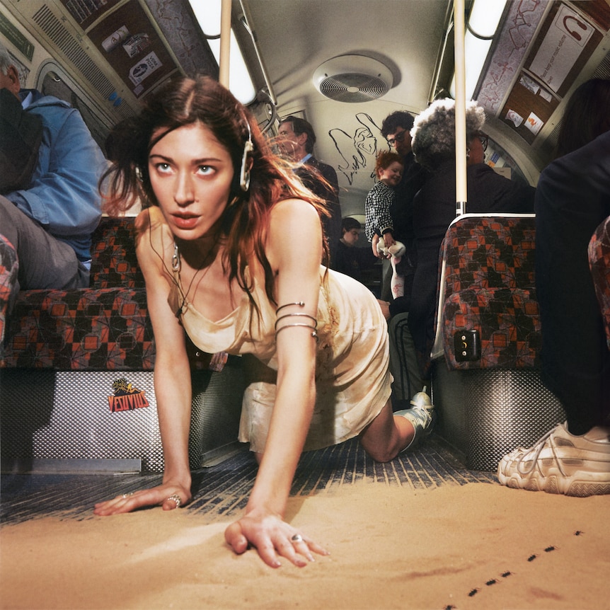 caroline polachek crawls through the carriage of a passenger train on her hands and knees