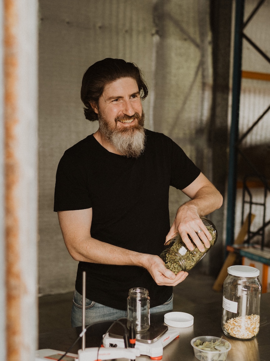 Man in a distillery, measuring ingredients