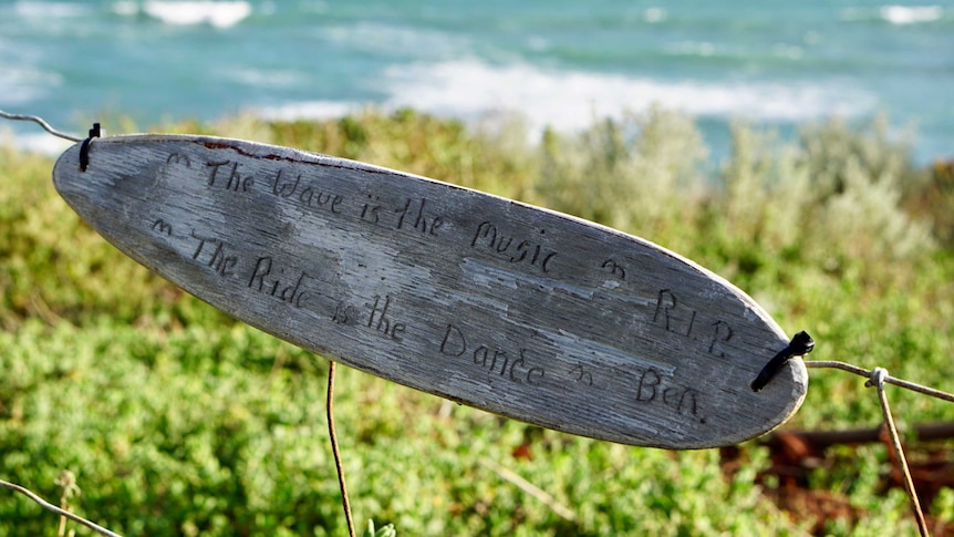 A wooden memorial shaped like a surf board attached to a fence near where Ben Gerring was fatally attacked by a shark