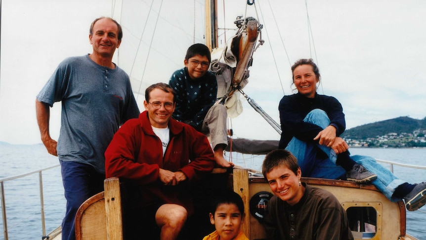 A family of mum, dad and four children on a yacht at sea.