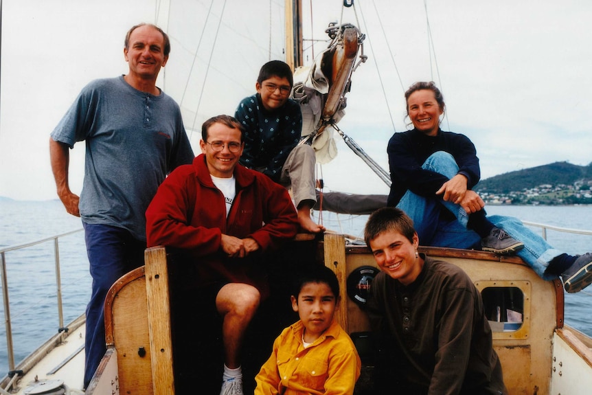 A family of mum, dad and four children on a yacht at sea.