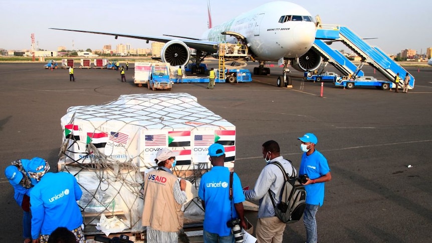 Aid workers check a shipment of coronavirus vaccines sent to Sudan by the Covax vaccine-sharing initiative