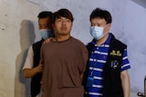 A Hong Kong man flanked by two other men walking.