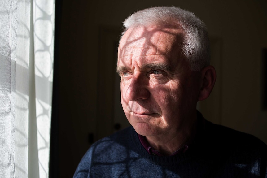 Burnie-Wynyard Parish priest Father John Girdauskas sits next to a window, June 2019.