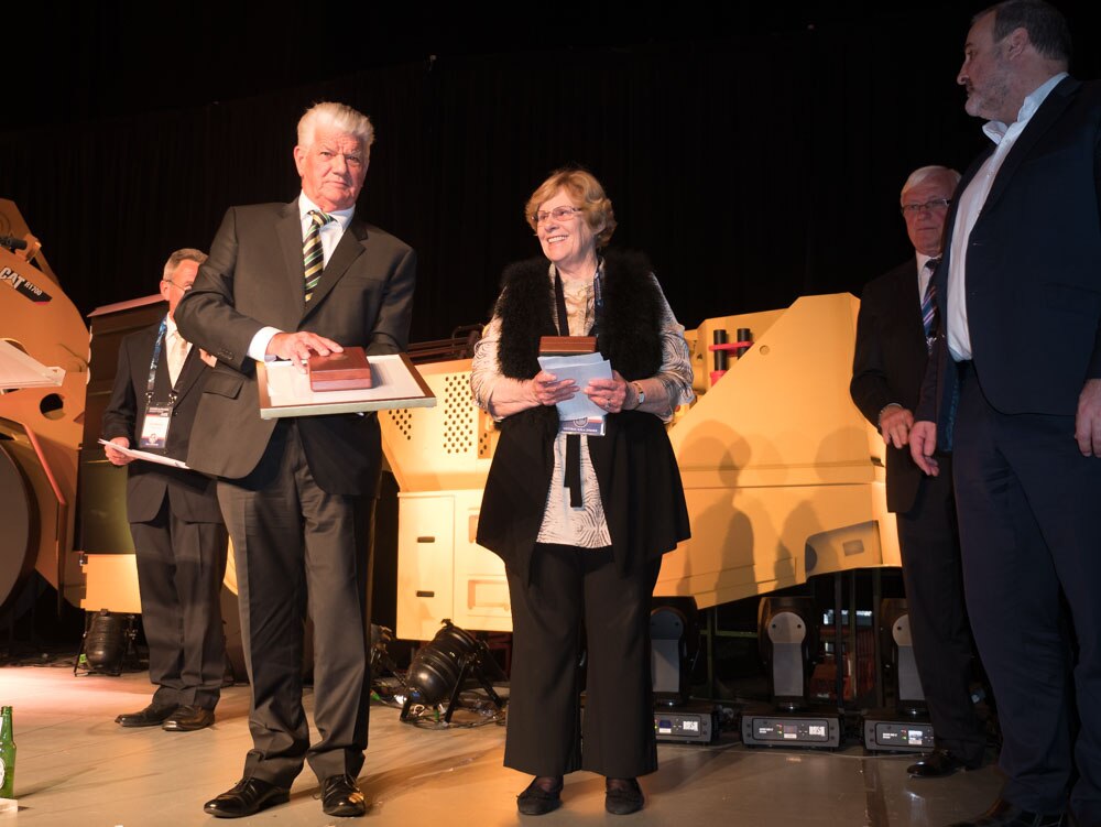 A man in a suit receives an award from a woman. 