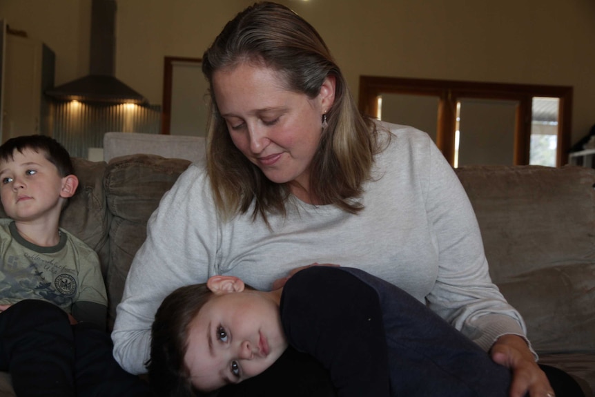 Holly Jessop smiles at her son Riley, 4, in her lap with her eldest Jack, 6, sitting to the left.