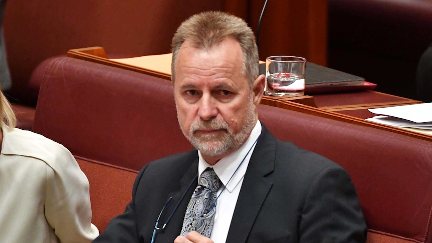 Nigel scullion removes his glasses in the senate chamber