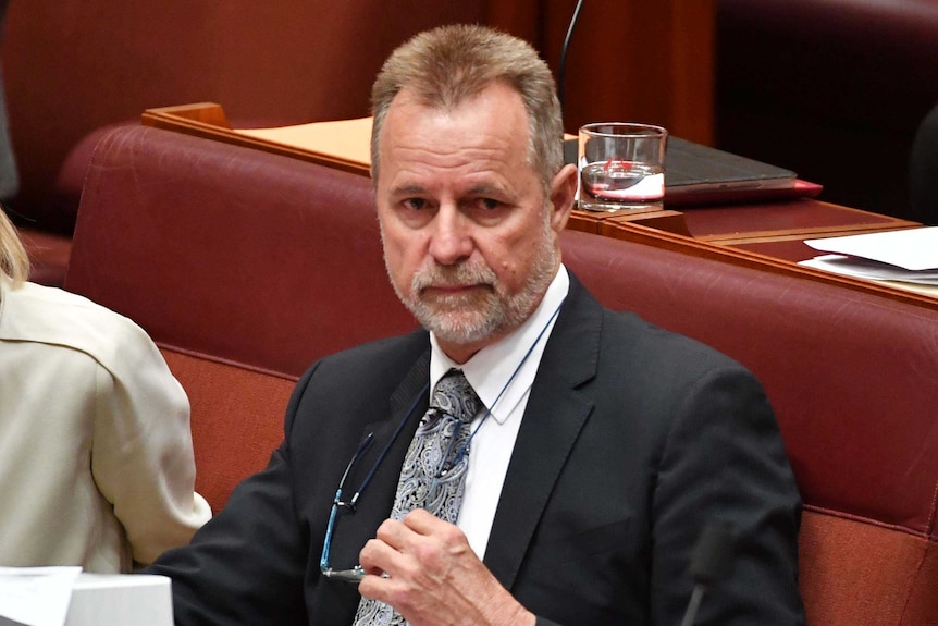 Nigel scullion removes his glasses in the senate chamber