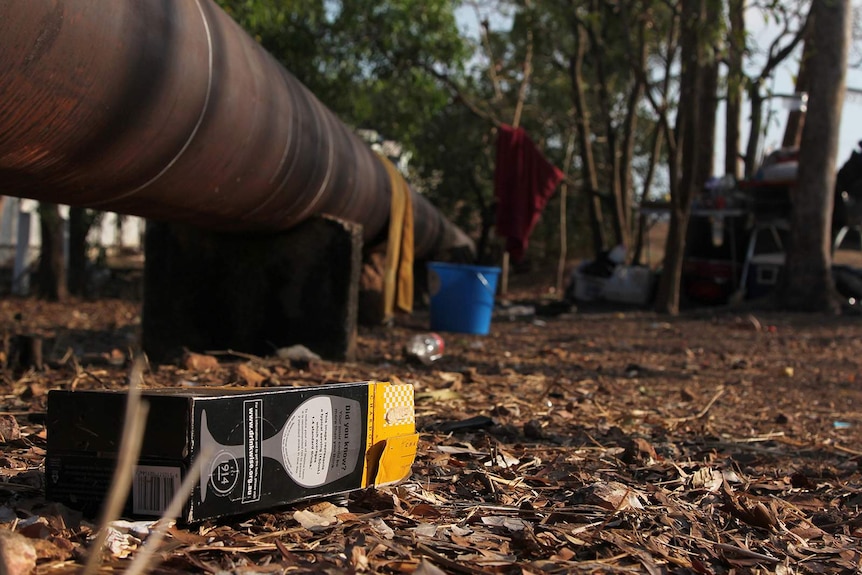 A photo of an empty box of cask wine in close-up in front of a drinking camp.