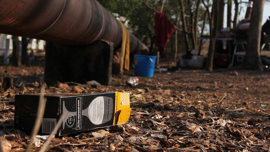 A photo of an empty box of cask wine in close-up in front of a drinking camp.