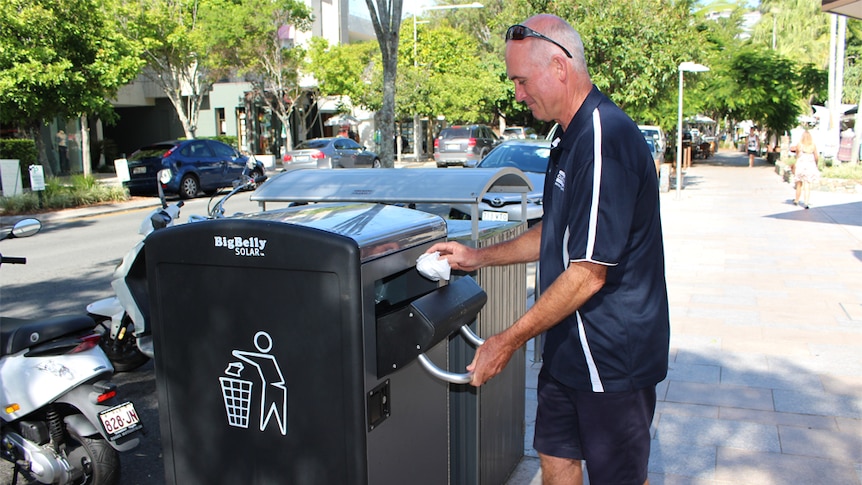 A councillor worker with the self-compacting solar bin at Noosa Heads.