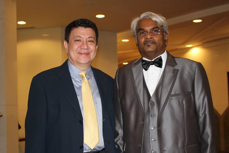 Sivakumar Ganapathy wearing a silver suit, standing next to Philip Mills who heads AsiaPR's presence in Phnom Penh