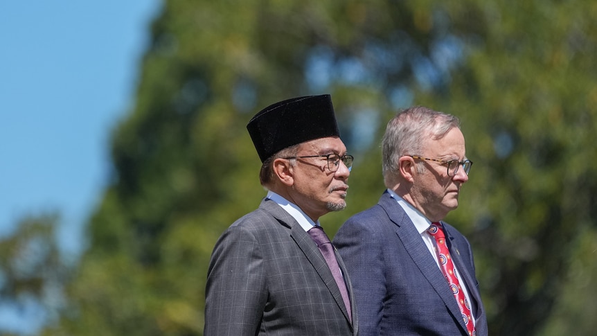 Anwar Ibrahim and Anthony Albanese stand next to each other, solemnly looking out into the distance