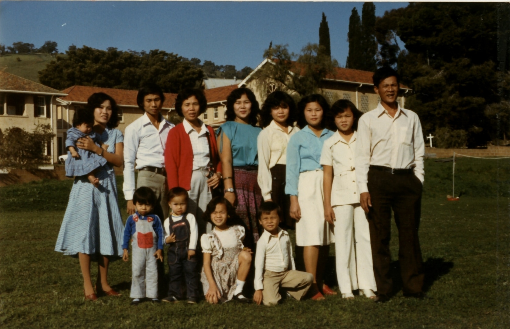 Photo of a large family standing for a family photo in front of houses.
