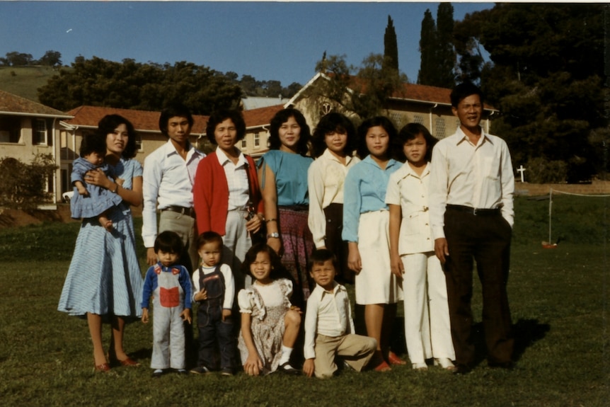 Photo of a large family standing for a family photo in front of houses.