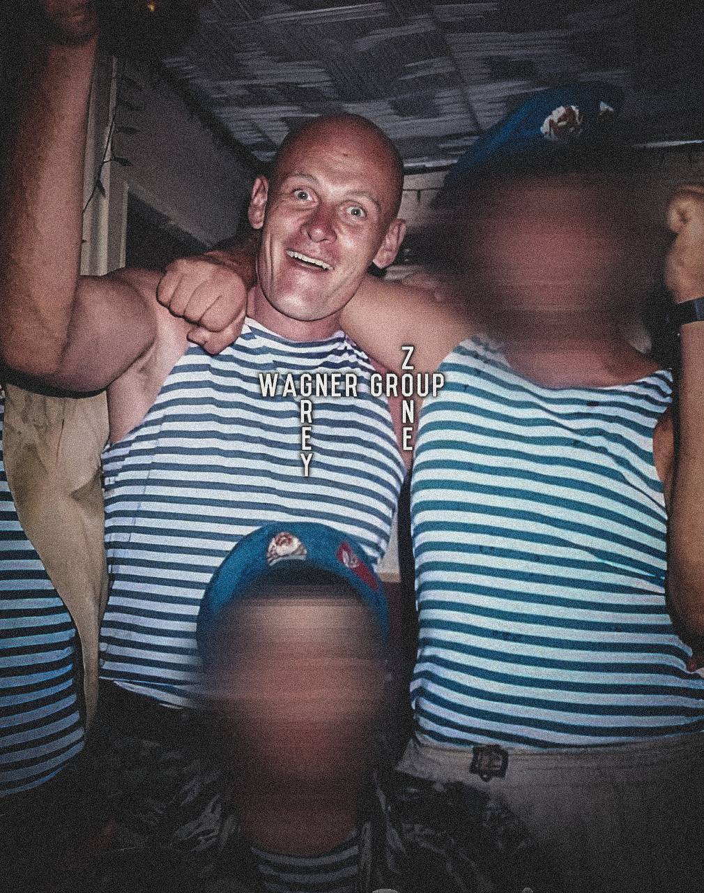 A close up of a man wearing a striped blue shirt with his arms around another man.