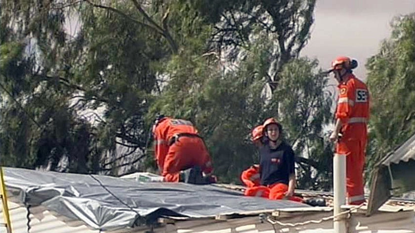 SES volunteers work on a storm-damaged roof