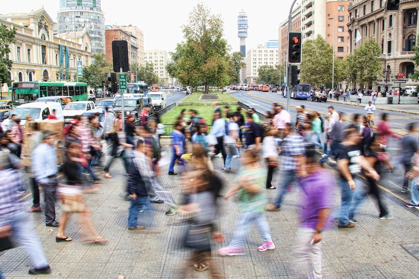 A crowd of people walking across a busy street
