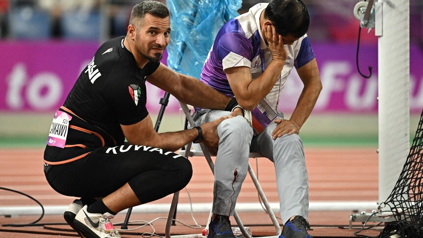 Ali Zankawi holds the leg of an official