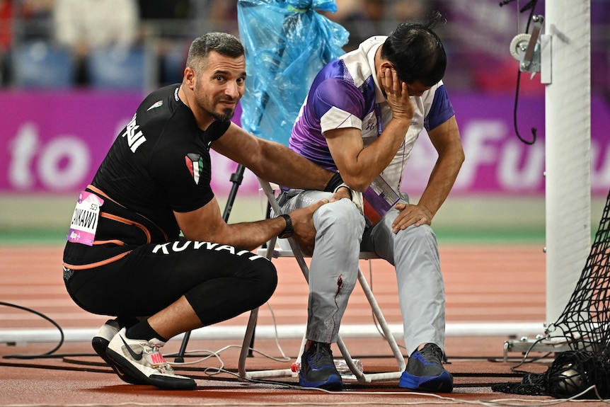 Ali Zankawi holds the leg of an official