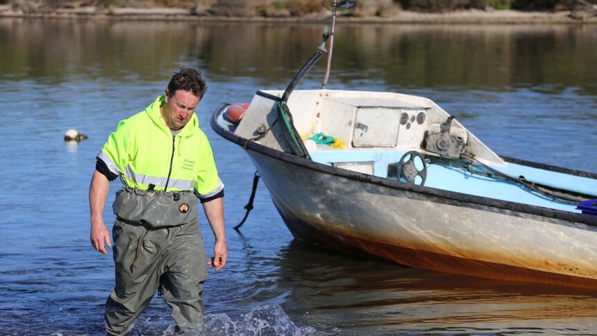 Matthew Allen walks through the water around his fishing boat.