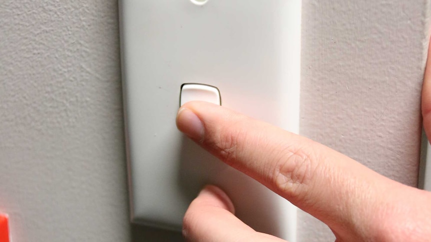 A hand turns on a light switch.