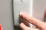A hand turns on a light switch.