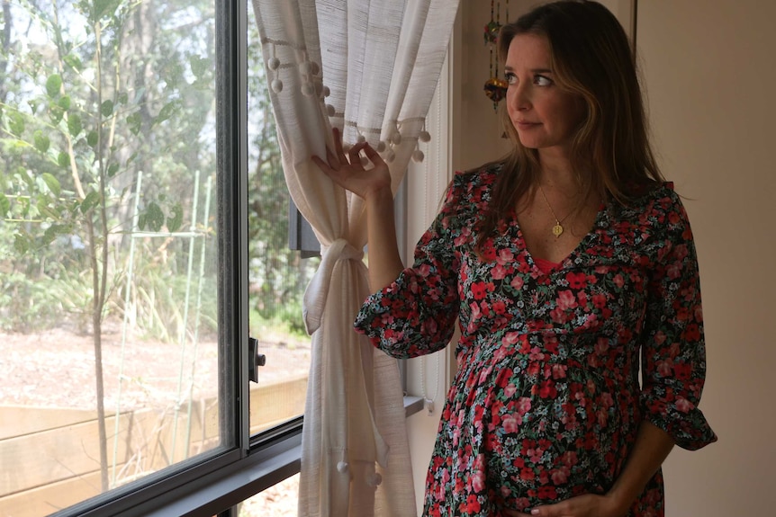 Pregnant woman looks out her window at the smoke