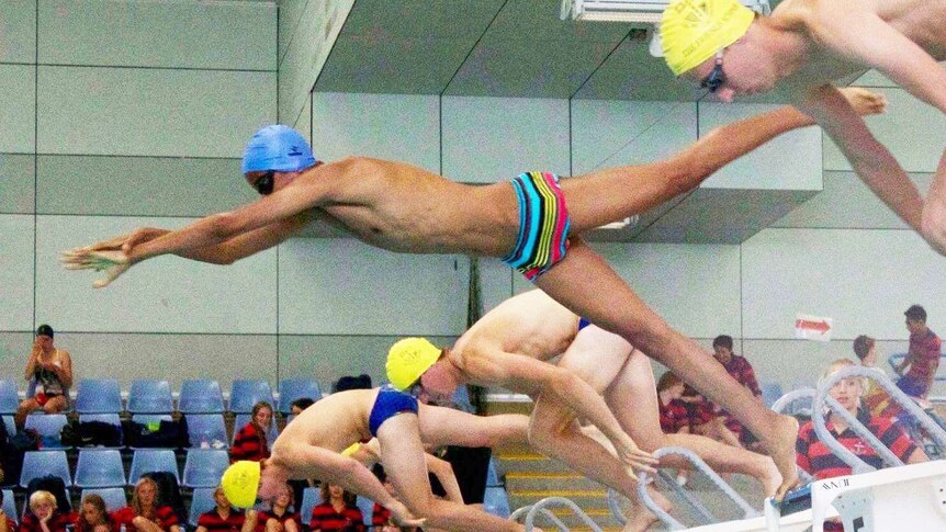 Swimmer Ahmed Awad leaps off the block alongside competitors.