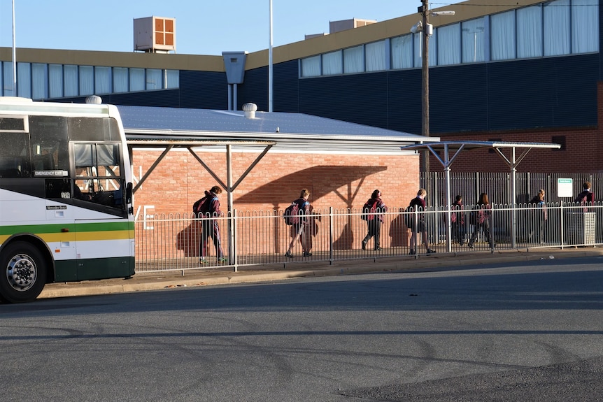 Children walk along a footpath near a bus stop.