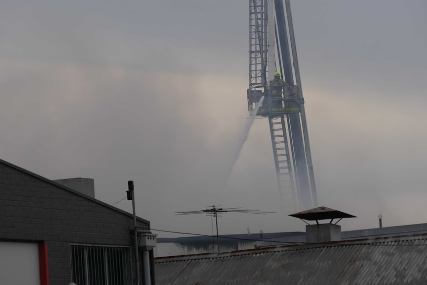 A firefighter uses a hose to spray water from a crane at Auburn.